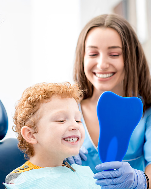 young child patient viewing their smile in a mirror with their parent
