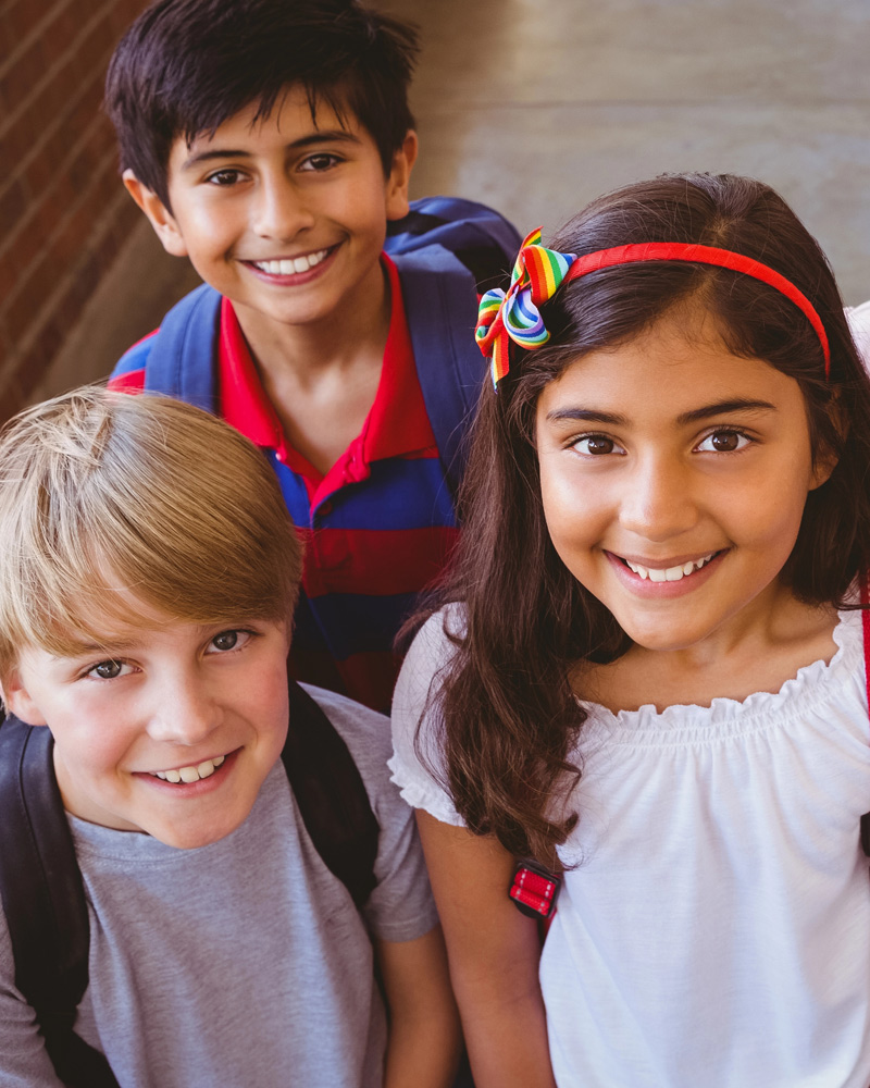 Three smiling children wearing backpacks | Dental health | Kids Orthodontics
